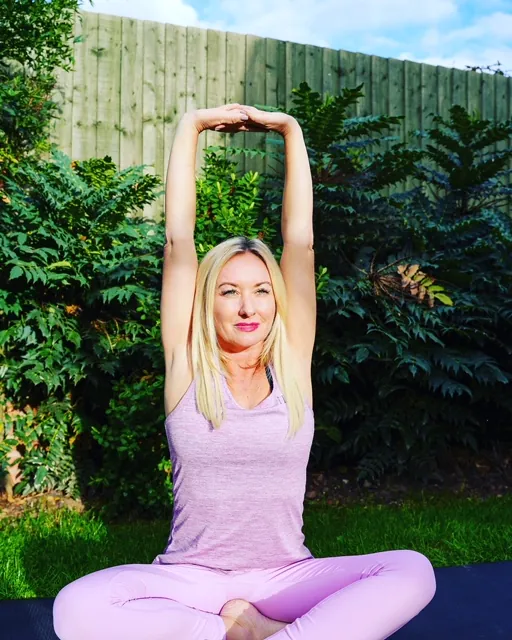 Seated Pilates stretch on a mat outdoors